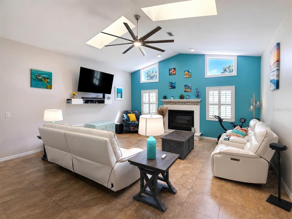 A living room features a white sofa, a fireplace on a blue wall, and tile flooring — 8930 BROOKER DRIVE, NEW PORT RICHEY, FL