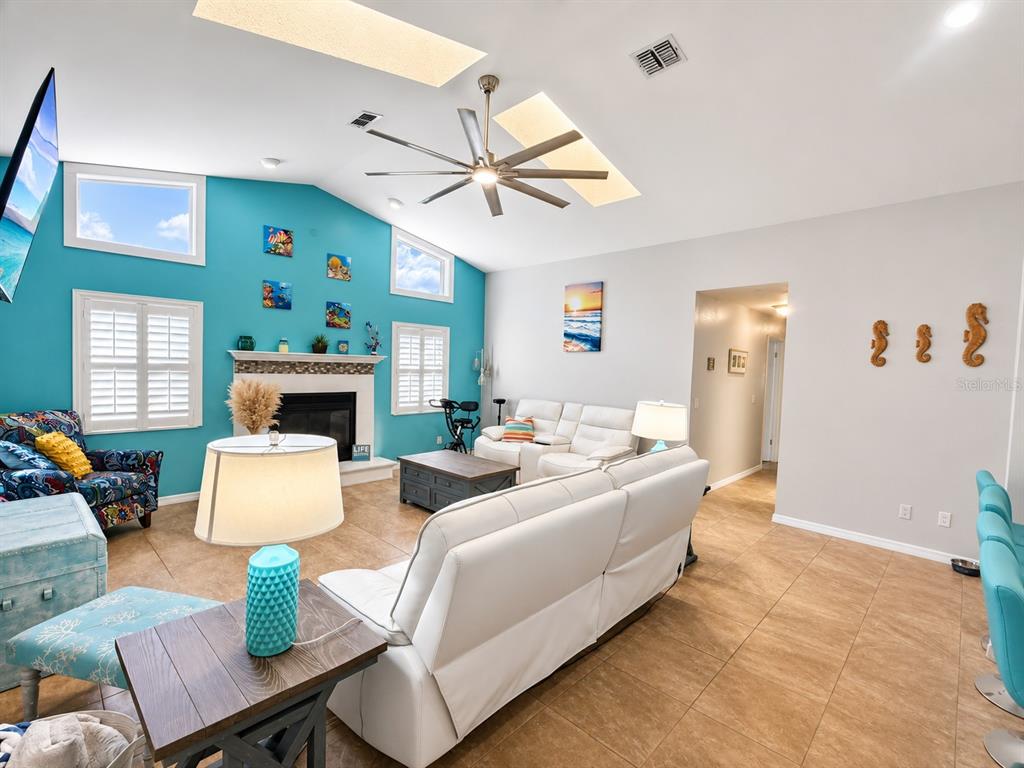 A living room features a turquoise accent wall, a fireplace, and white leather furniture — 8930 BROOKER DRIVE, NEW PORT RICHEY, FL