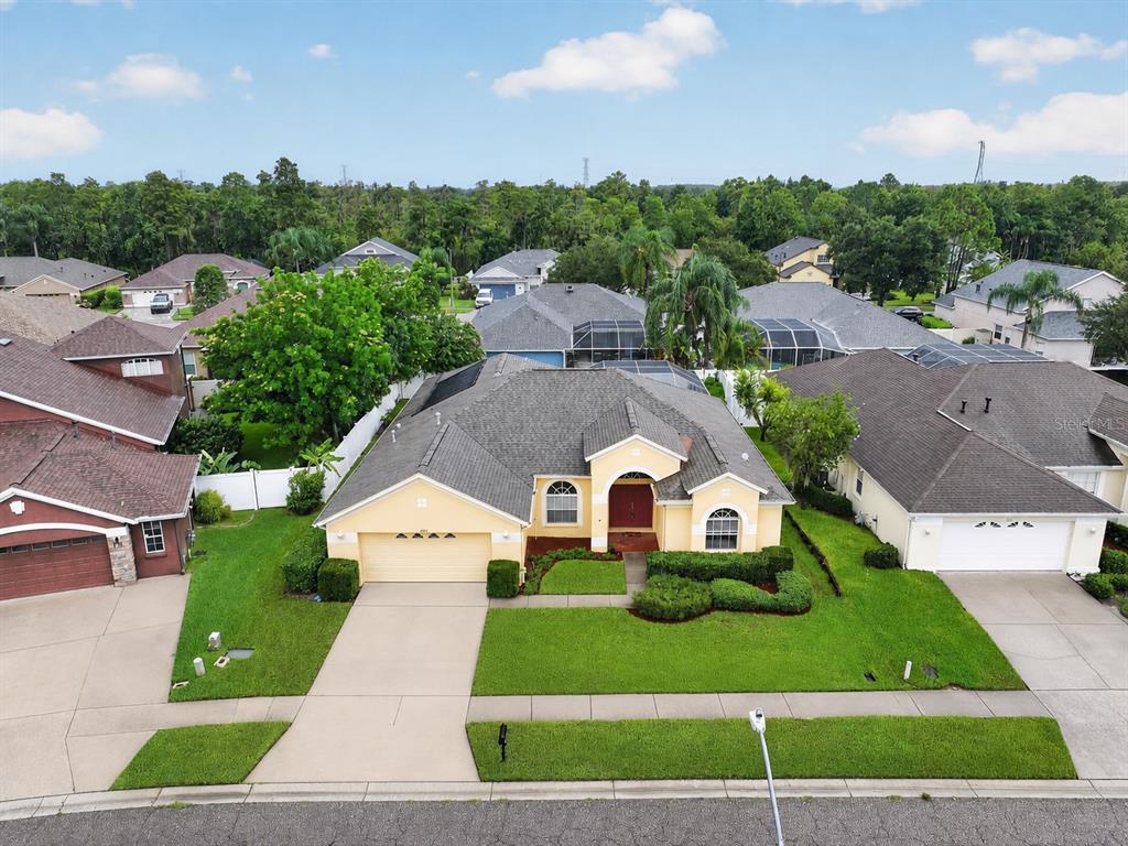 An aerial view shows a yellow single-story house with a gray roof and attached garage — 1549 KISH BOULEVARD, NEW PORT RICHEY, FL