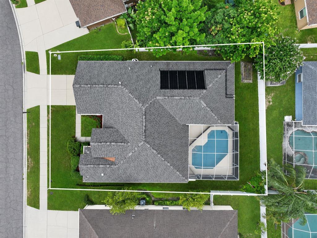 An aerial view shows a house with a shingled roof, solar panels, and a screened pool — 1549 KISH BOULEVARD, NEW PORT RICHEY, FL