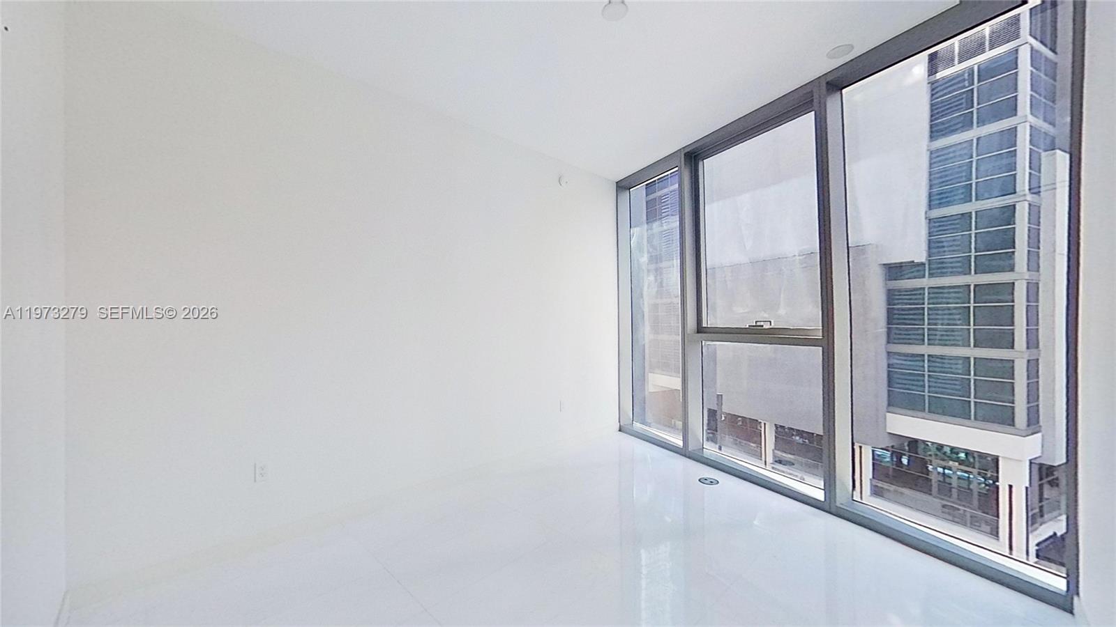 An empty room features white walls, glossy white flooring, and floor-to-ceiling windows — 300 Biscayne Boulevard Way # 506E, Miami FL 33131, MIAMI, FL