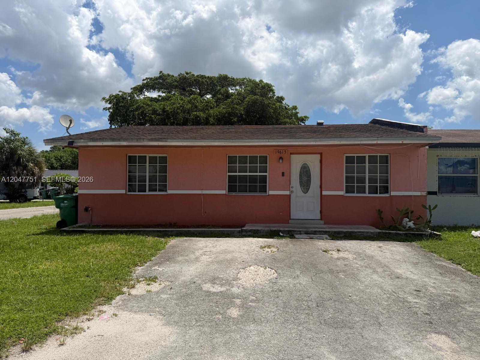 A single-story pink house with a white trim, a front door, and a paved driveway — MIAMI GARDENS, FL