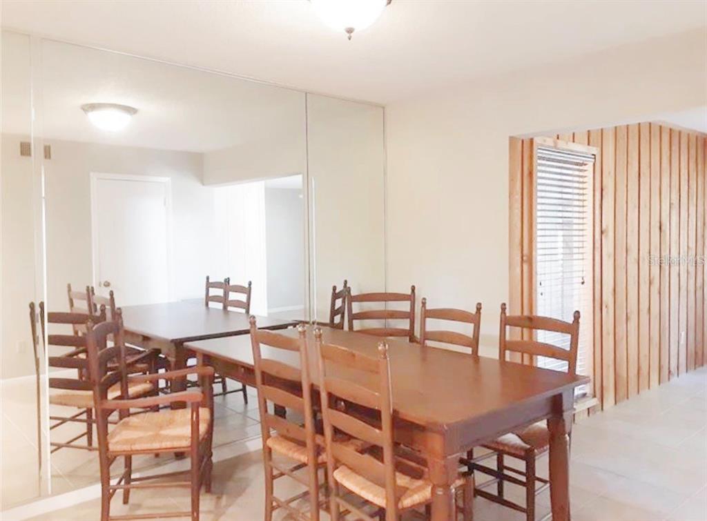 A dining room features a wooden table, matching chairs, and a large mirrored wall — 1056 E MICHIGAN STREET UNIT 1056A, ORLANDO, FL