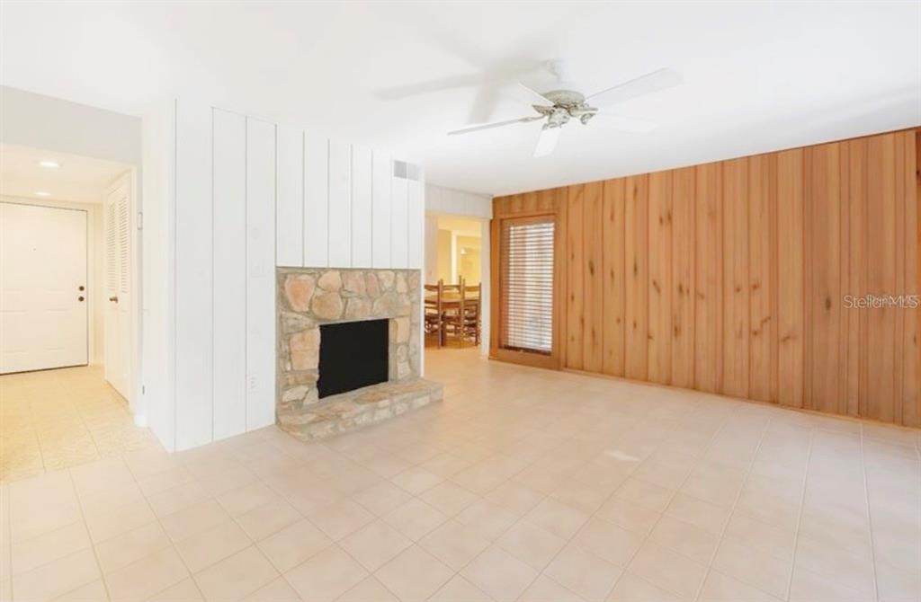 A living room features a stone fireplace, white vertical paneling, and a wood-paneled wall — 1056 E MICHIGAN STREET UNIT 1056A, ORLANDO, FL