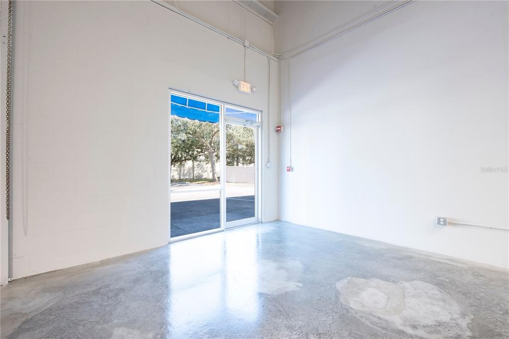 An empty commercial space with white concrete block walls, a polished floor, and an exit door — 7307 SANDSCOVE COURT UNIT 5, WINTER PARK, FL