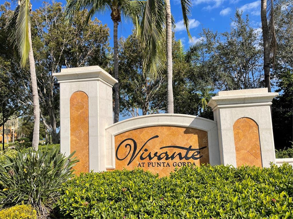 A stone monument sign for Vivante at Punta Gorda stands amidst palm trees and landscaping — 85 VIVANTE BOULEVARD UNIT 8534, PUNTA GORDA, FL