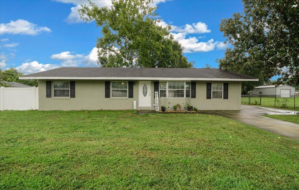 A single-story, light green brick house with black shutters and a white front door — 11793 SE 72ND TERRACE ROAD, BELLEVIEW, FL