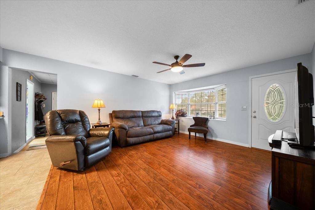 A living room features hardwood floors, a leather sofa, a recliner, and a bay window — 11793 SE 72ND TERRACE ROAD, BELLEVIEW, FL