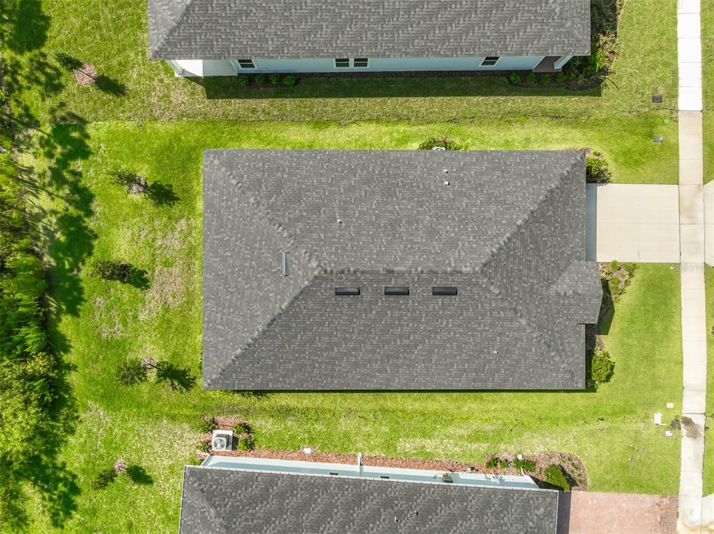 An aerial view shows a residential house with a gray shingled roof and surrounding lawn — 8 AUCILLA PLACE, PALM COAST, FL