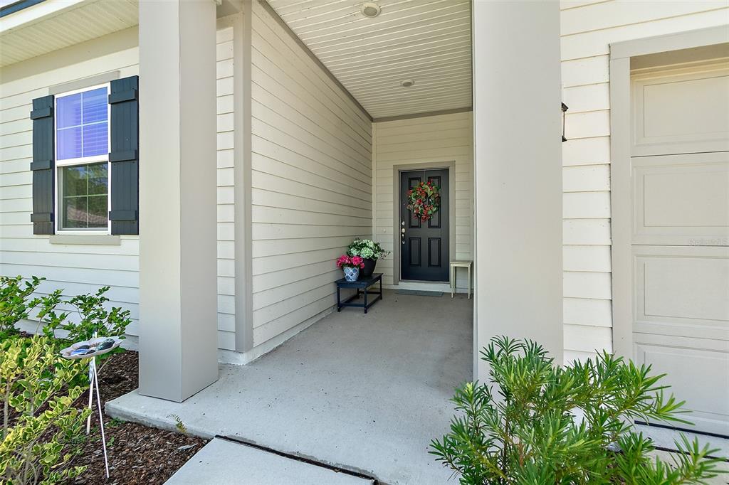 A covered entryway features a dark front door with a wreath and a small side table — 8 AUCILLA PLACE, PALM COAST, FL