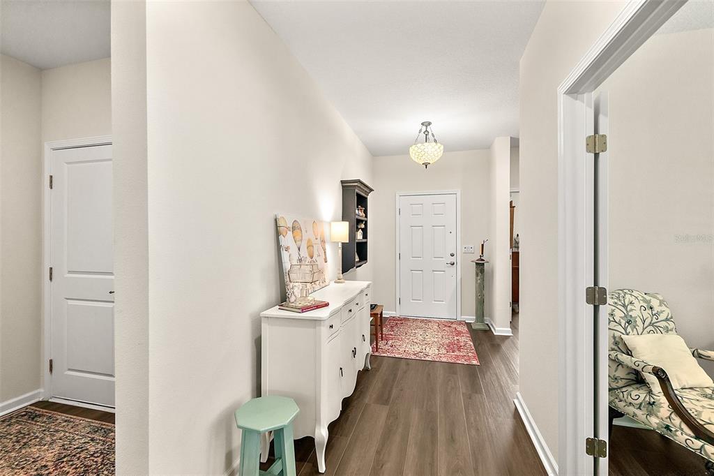 A bright entryway features wood-look flooring, a white console table, and a front door — 8 AUCILLA PLACE, PALM COAST, FL