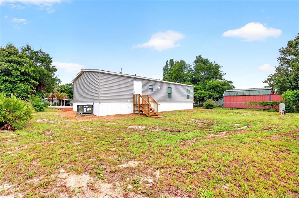 A gray manufactured home with a wooden staircase sits on a grassy lot — 1540 SE 187TH AVENUE, SILVER SPRINGS, FL