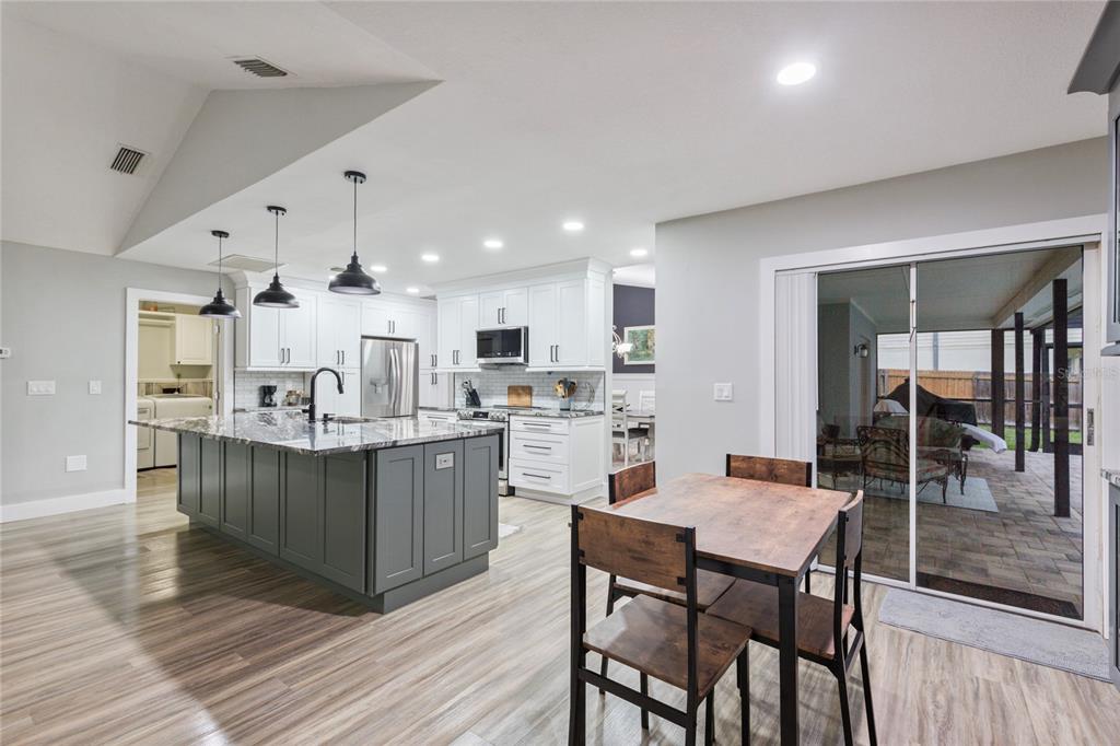 A modern kitchen features a large dark gray island with a marble countertop and white cabinetry — 2766 BUCKHORN OAKS DRIVE, VALRICO, FL