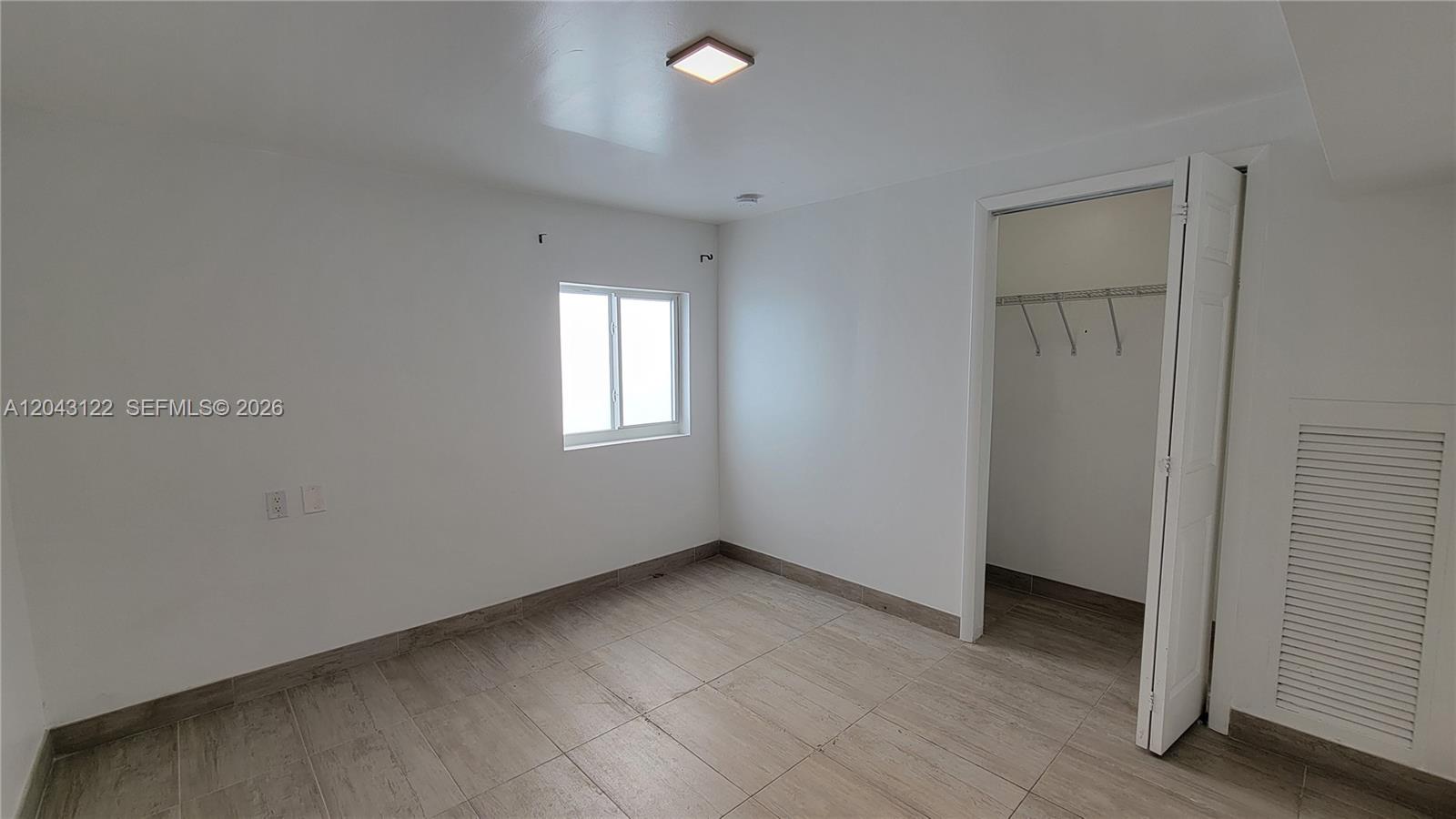 An empty room features white walls, light-colored tile flooring, a small window, and a closet — 14200 NE 15th Ave # B, North Miami FL 33161, NORTH MIAMI, FL