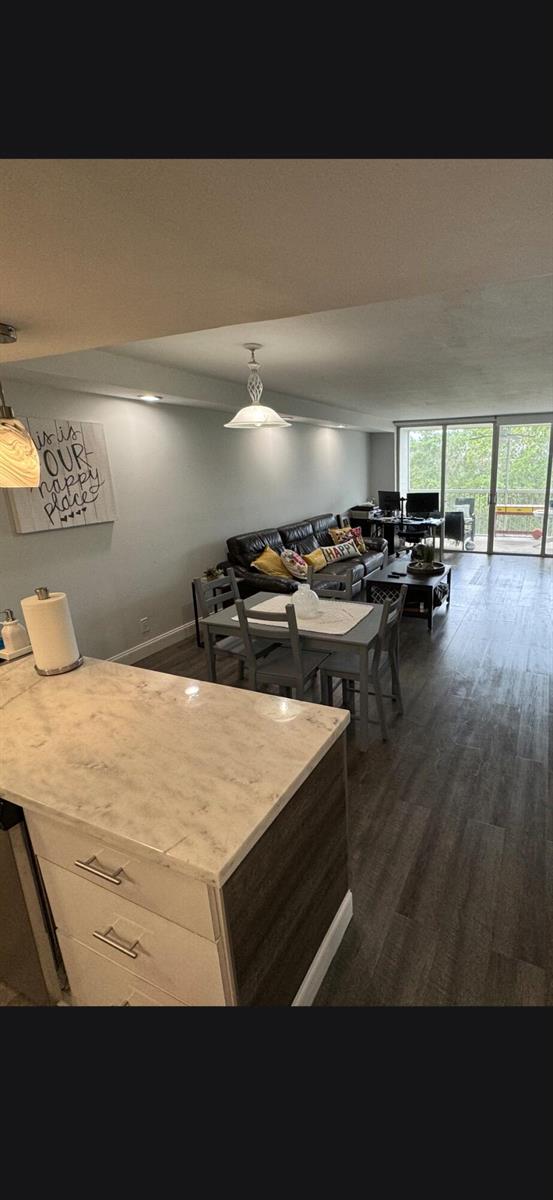 A kitchen island with a marble countertop overlooks an open-concept living and dining area — 3090 N Course Drive # 601, Pompano Beach FL 33069, POMPANO BEACH, FL