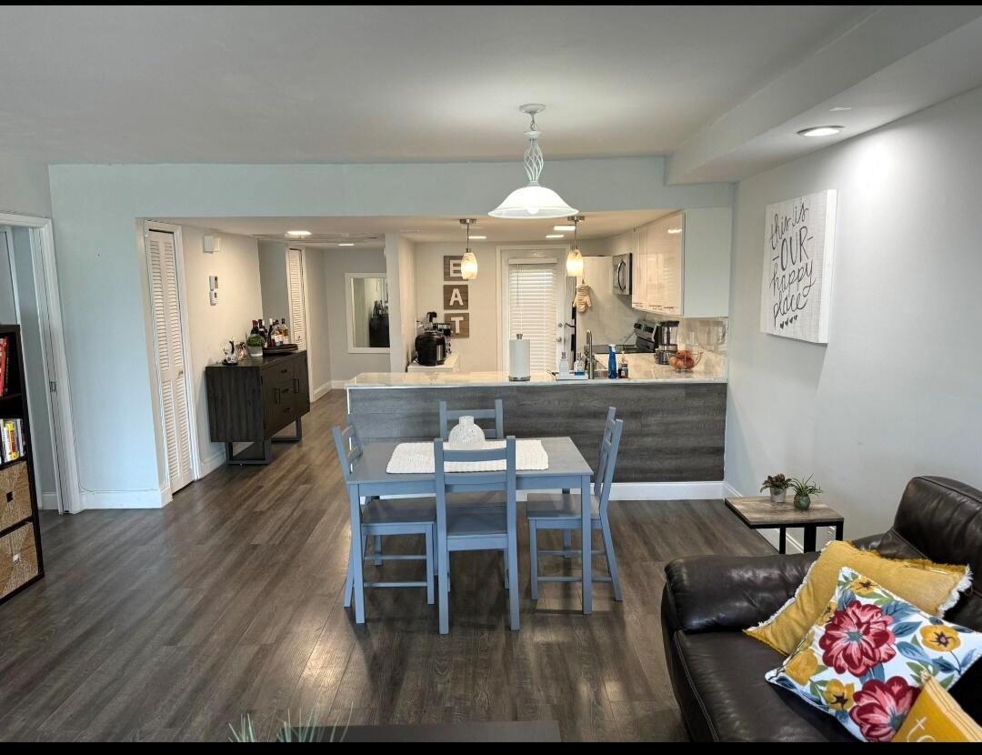 An open-concept dining area and kitchen feature gray wood-look flooring and a breakfast bar — 3090 N Course Drive # 601, Pompano Beach FL 33069, POMPANO BEACH, FL