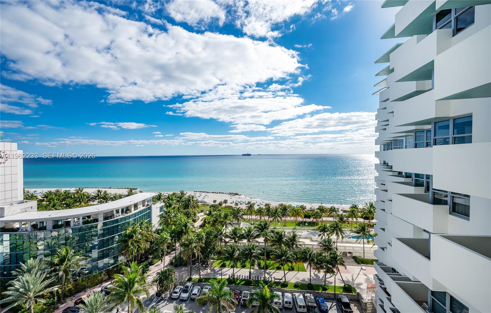 A living room features a white sectional sofa, dark wood flooring, and an ocean view — 2899 Collins Ave # 1505, Miami Beach FL 33140, MIAMI BEACH, FL
