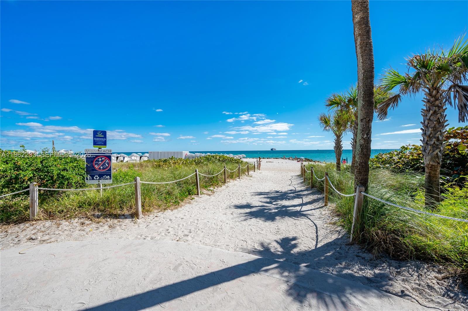 A bedroom features a white bed, a wall-mounted television, and a window overlooking the ocean — 2899 Collins Ave # 1505, Miami Beach FL 33140, MIAMI BEACH, FL