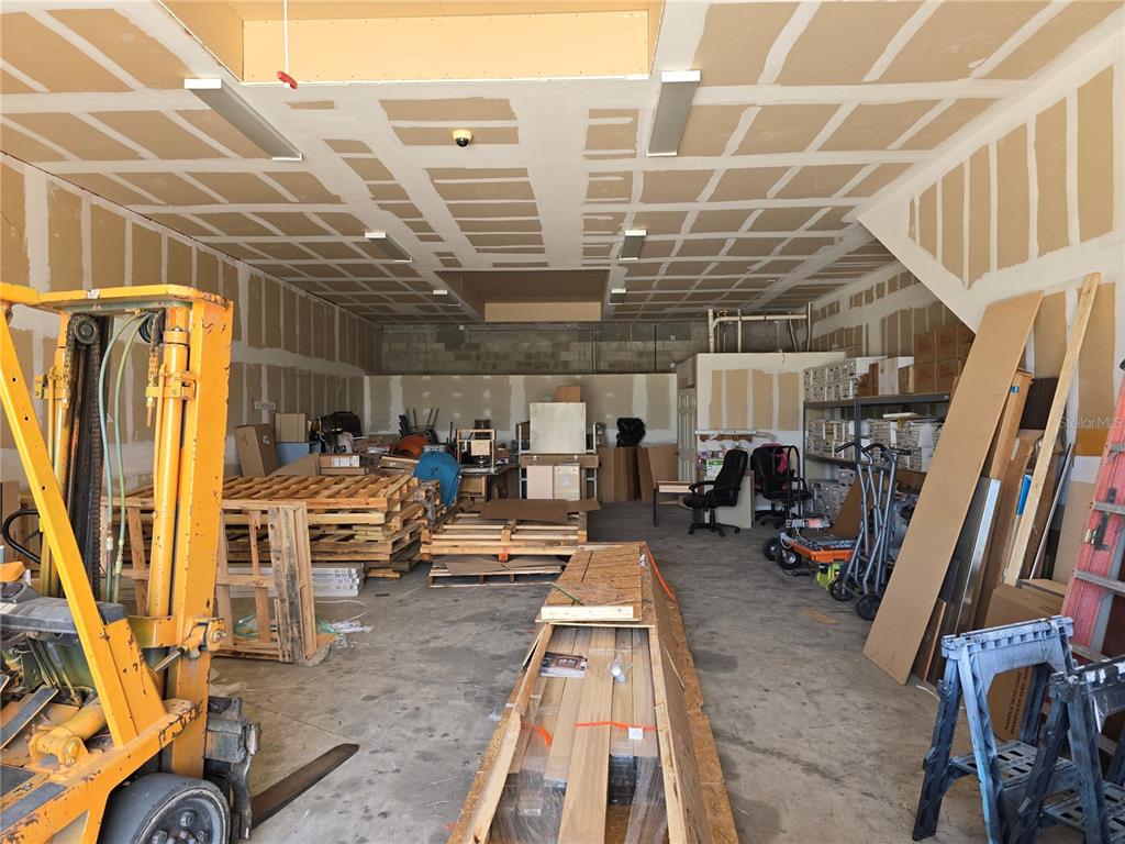 A warehouse space features a forklift, wooden pallets, and unfinished drywall on the walls — 3131 FOLEY DRIVE UNIT 2A, PORT CHARLOTTE, FL