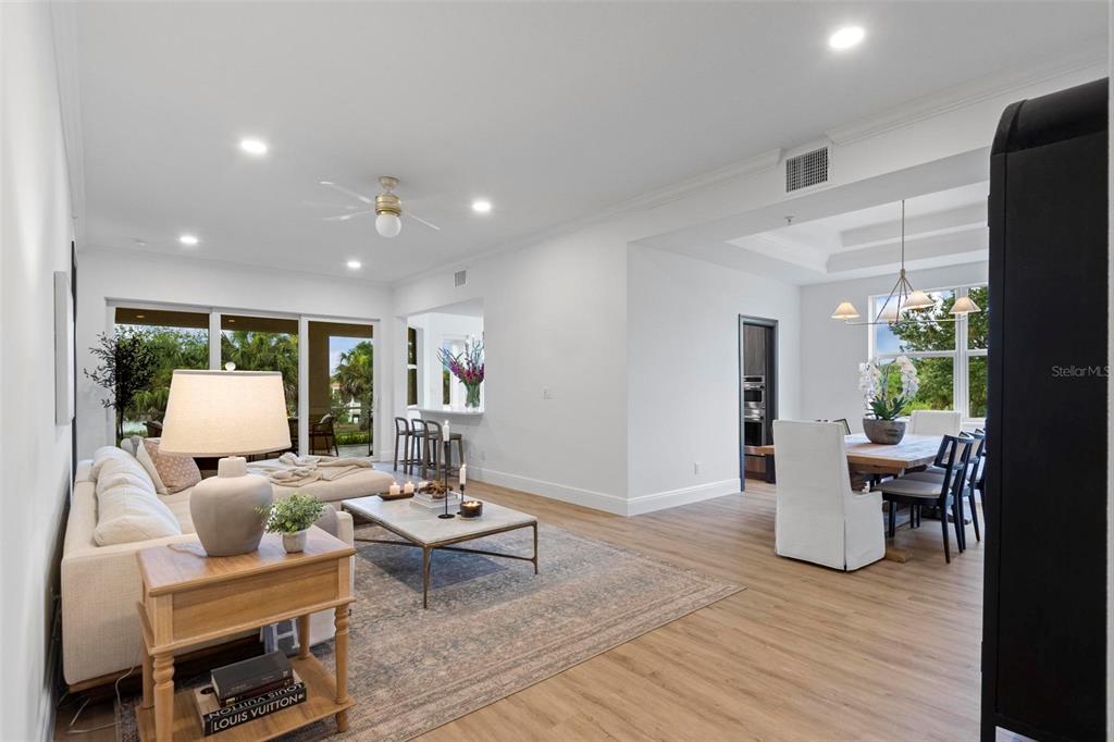 A bright, open-concept living and dining area features light wood flooring and large glass doors — 455 RIVERFRONT DRIVE UNIT A104, PALM COAST, FL