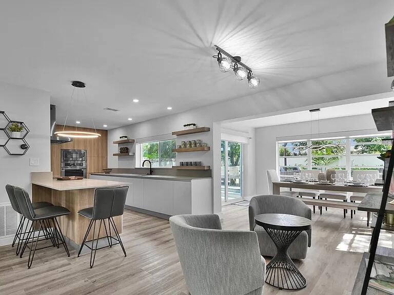 A modern open-concept kitchen and dining area features light wood flooring and neutral cabinetry — 803 Bluebird Drive, Delray Beach FL 33444, DELRAY BEACH, FL