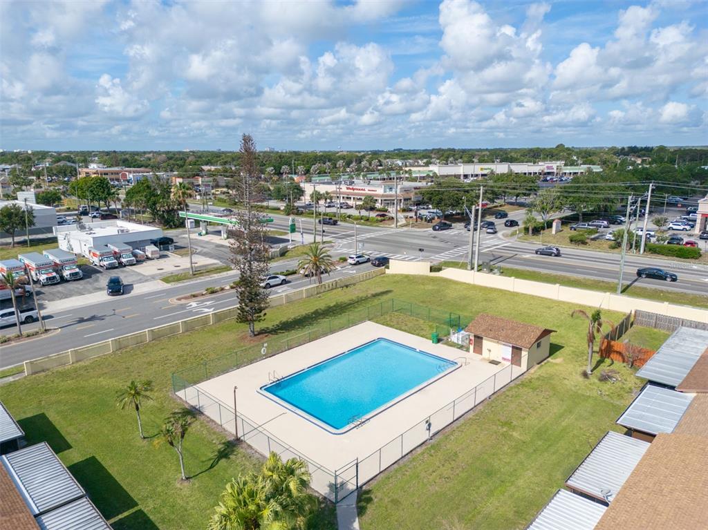 An aerial view shows a rectangular swimming pool enclosed by a fence near a road — 48 HEPBURN PLACE, MERRITT ISLAND, FL