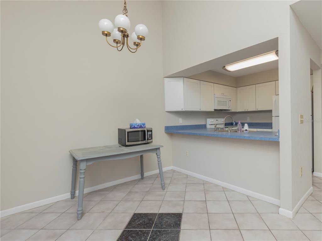 A dining area with a chandelier and table sits adjacent to a kitchen with blue countertops — 4356 SW 20TH LANE, GAINESVILLE, FL