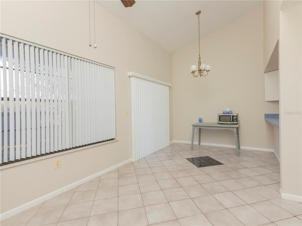 A dining area features tile flooring, a chandelier, vertical blinds, and a small table — 4356 SW 20TH LANE, GAINESVILLE, FL