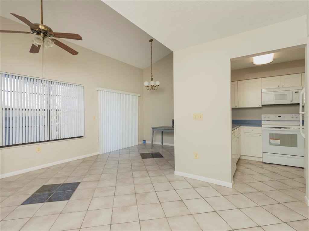 A dining area with tile floors and a ceiling fan opens into a white kitchen — 4356 SW 20TH LANE, GAINESVILLE, FL