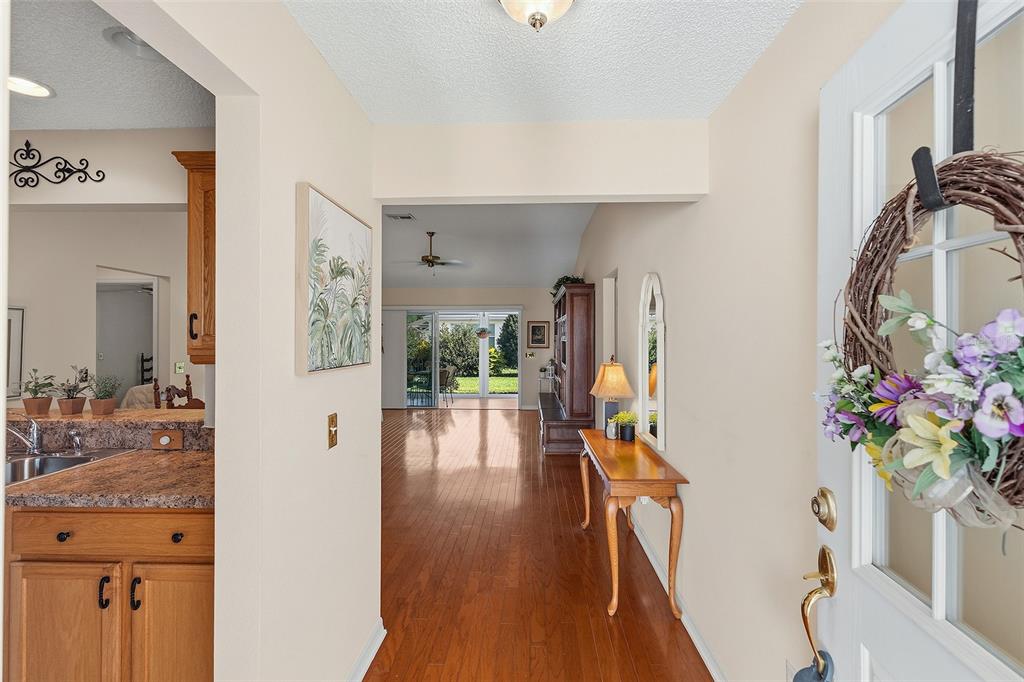 A view from an entryway looking into a living area with hardwood floors and patio doors — 1681 SHELBURNE LANE, THE VILLAGES, FL