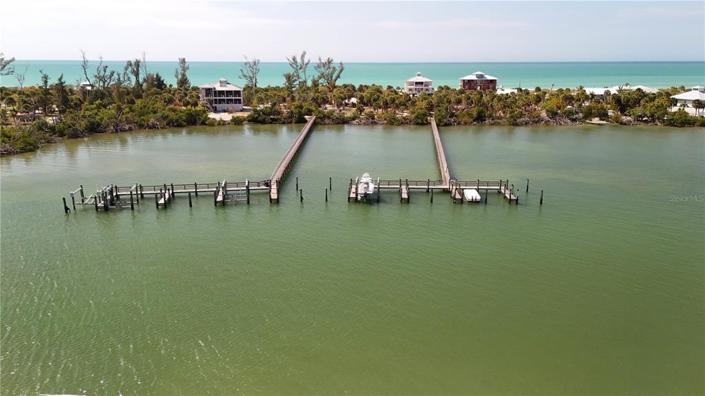 An aerial view shows two long wooden docks extending into a calm bay — 9160 GRAND AVENUE, PLACIDA, FL