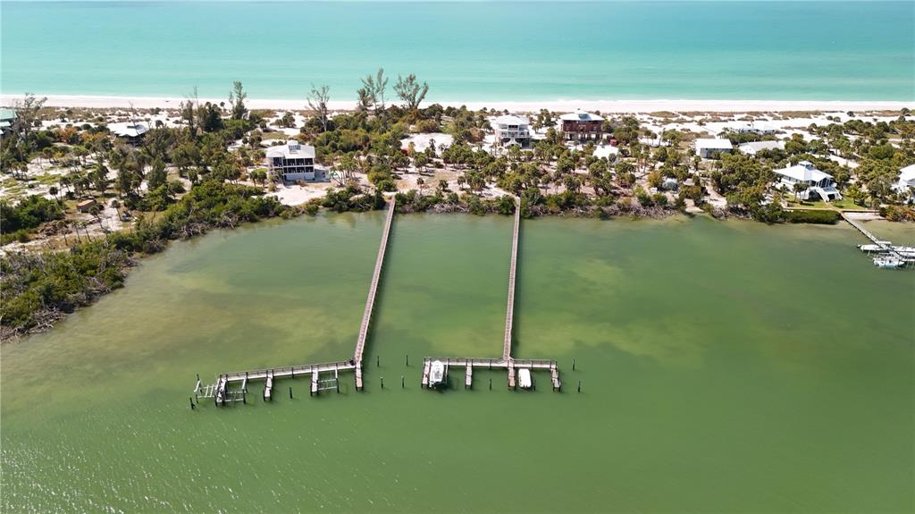 An aerial view shows a long wooden dock extending into a bay near coastal homes — 9160 GRAND AVENUE, PLACIDA, FL