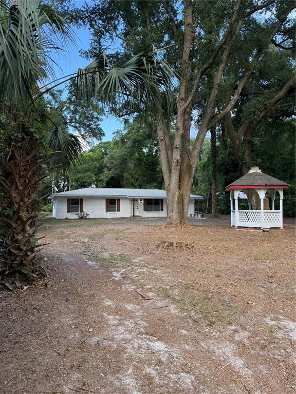 A white, single-story house with a gazebo sits on a wooded lot — 6989 SW STATE ROAD 26, TRENTON, FL