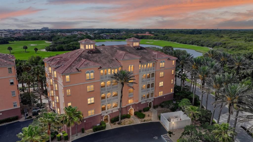 An aerial view of a multi-story peach-colored apartment building overlooking a golf course and pond — 35 OCEAN CREST WAY UNIT 1111, PALM COAST, FL