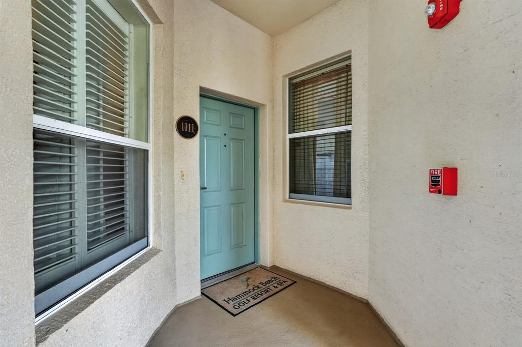 A light blue front door with the number 1111 is centered between two windows — 35 OCEAN CREST WAY UNIT 1111, PALM COAST, FL