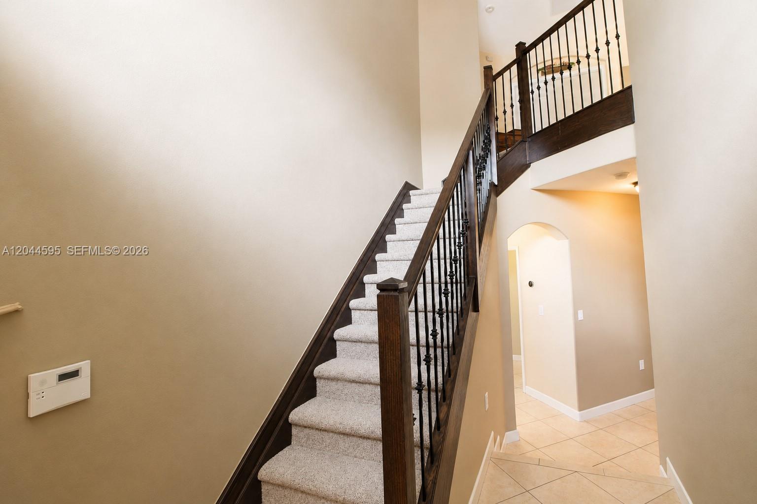 A staircase with carpeted steps and dark wood railings leads to an upper landing — 13989 SW 155th Ter, Miami FL 33177, MIAMI, FL