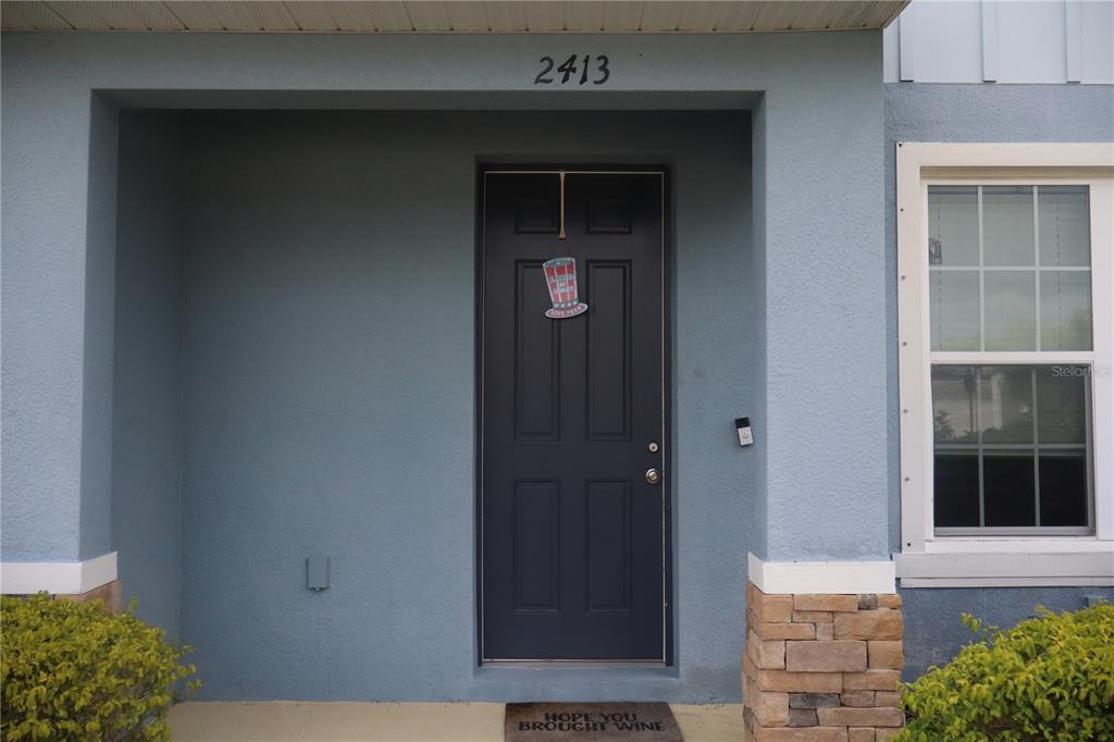 A two-story blue townhouse exterior features multiple windows with dark shutters and covered entryways — 2413 GATHERING WAY, ODESSA, FL