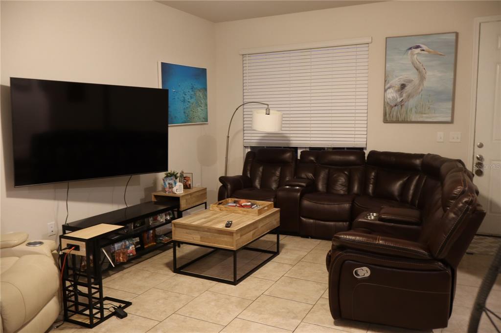 A small seating area features two chairs, a glass table, and wall art against a blue wall — 2413 GATHERING WAY, ODESSA, FL