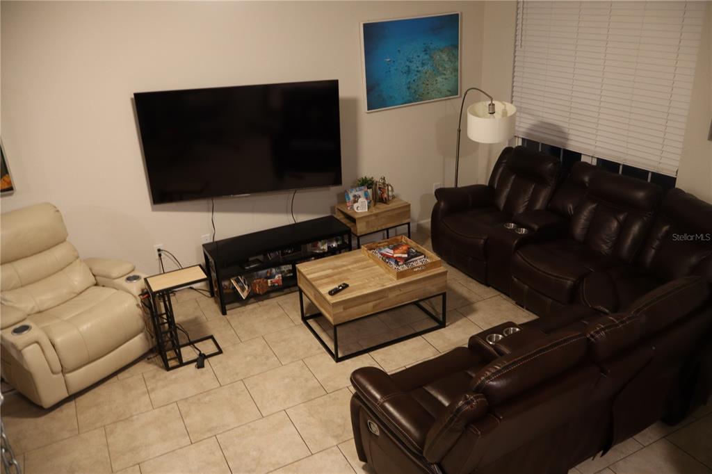 A living room features a large television, a brown leather sectional, and a wooden coffee table — 2413 GATHERING WAY, ODESSA, FL