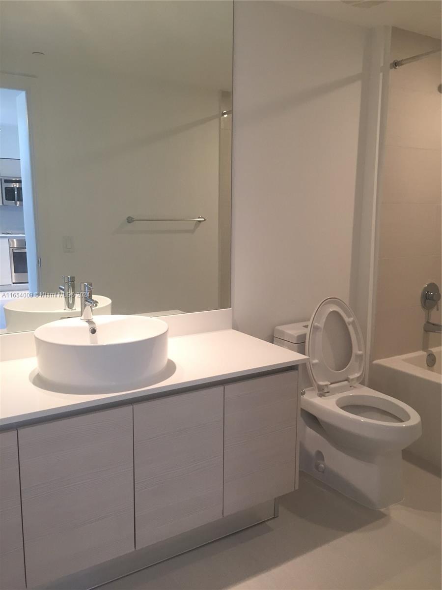 A modern bathroom features a white vessel sink, light wood cabinetry, and a toilet — 4250 Biscayne Blvd # 1211, Miami FL 33137, MIAMI, FL
