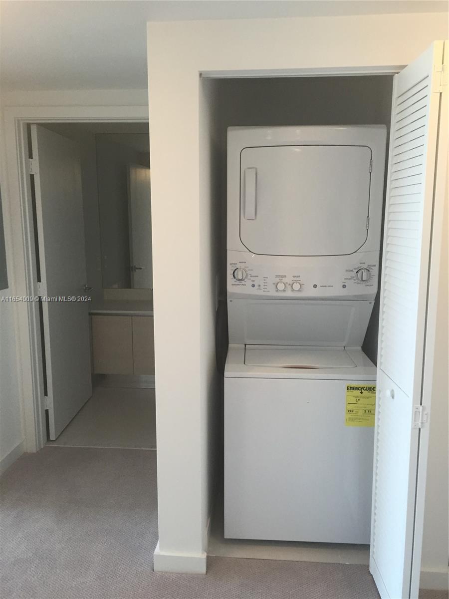 A stacked washer and dryer unit is located in a closet next to a bathroom — 4250 Biscayne Blvd # 1211, Miami FL 33137, MIAMI, FL