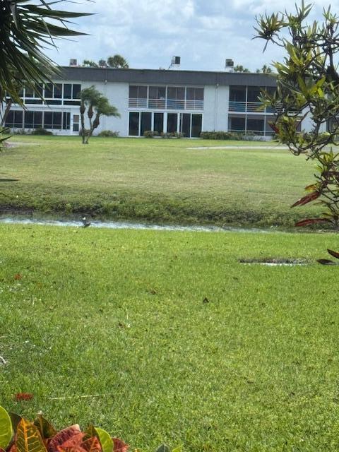 A multi-story apartment building sits behind a grassy lawn and a small canal — 6 Normandy A, Delray Beach FL 33484, DELRAY BEACH, FL