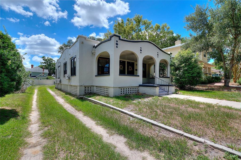 A single-story stucco house with a curved parapet roof and an arched front porch — 728 JOHNSON AVENUE, LAKELAND, FL