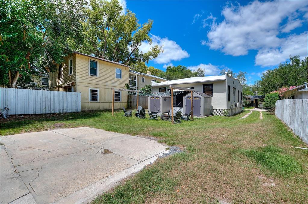 A backyard features a concrete patio, two storage sheds, and a wooden pergola — 728 JOHNSON AVENUE, LAKELAND, FL