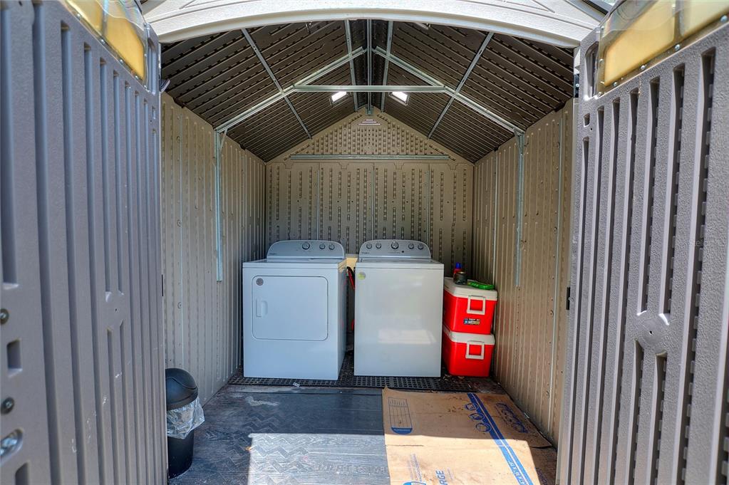 A plastic storage shed contains a white washer and dryer and two stacked red coolers — 728 JOHNSON AVENUE, LAKELAND, FL