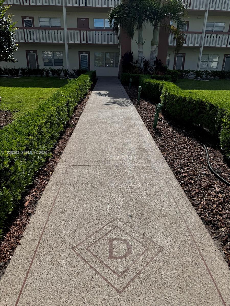 A concrete walkway leads toward the entrance of a multi-story apartment building — 149 Preston D # 149, Boca Raton FL 33434, BOCA RATON, FL