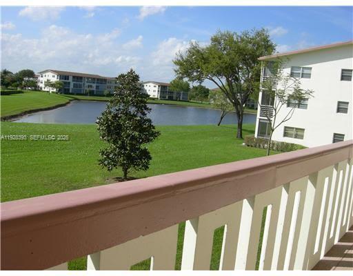 A balcony view overlooking a grassy lawn, a small pond, and multi-story apartment buildings — 149 Preston D # 149, Boca Raton FL 33434, BOCA RATON, FL