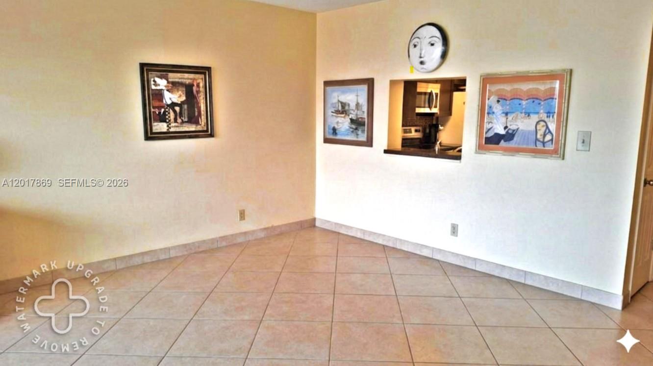 An interior view shows a tiled room with three framed pictures and a kitchen pass-through — 401 NE 14th Ave # 507, Hallandale Beach FL 33009, HALLANDALE BEACH, FL
