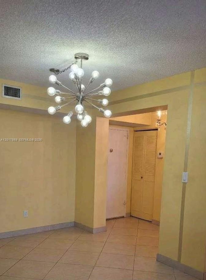 A room with yellow walls, tile flooring, and a modern sputnik-style chandelier — 401 NE 14th Ave # 507, Hallandale Beach FL 33009, HALLANDALE BEACH, FL