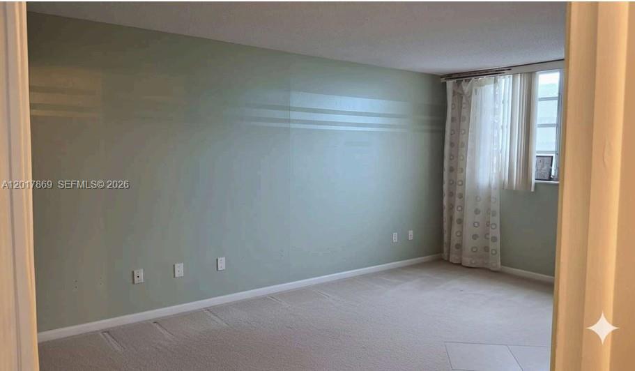 An empty room with light green walls, beige carpeting, and a window with vertical blinds — 401 NE 14th Ave # 507, Hallandale Beach FL 33009, HALLANDALE BEACH, FL